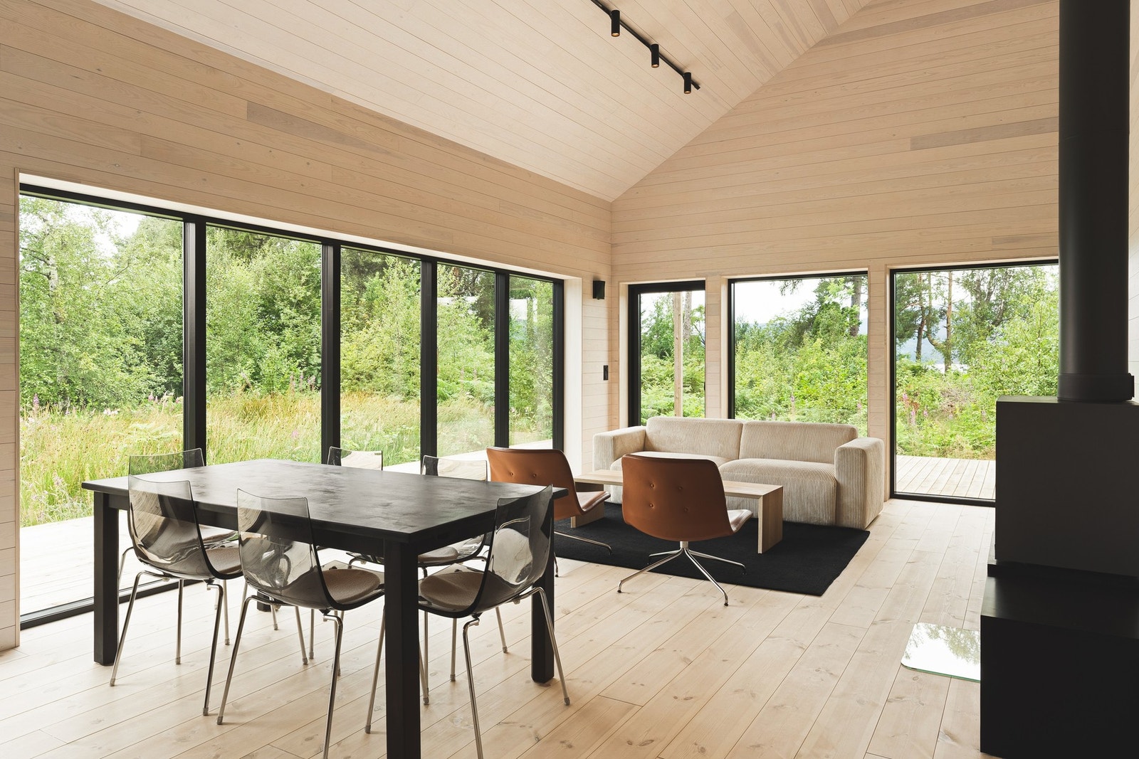 Herfra ledes du videre inn til hyttens naturlige samlingspunkt - en stor stue og kjøkken i åpen løsning, med en imponerende takhøyde og store vindusflater som skaper en luftig og lys atmosfære. Galleribilde