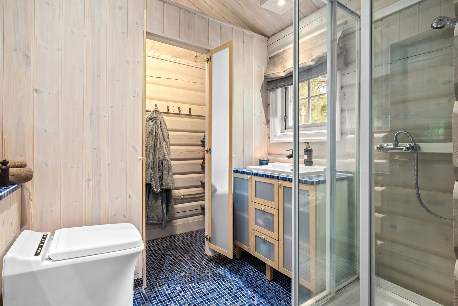 Badet er utstyrt med servant, forbrenningstoalett og dusjkabinett. Galleribilde