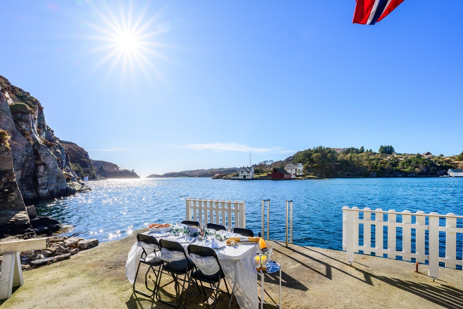 Perfekt setting for måltidet - bordet er dekket, solen skinner, og stigen på kaien tar deg rett til sjøen for en dukkert etter maten. Galleribilde