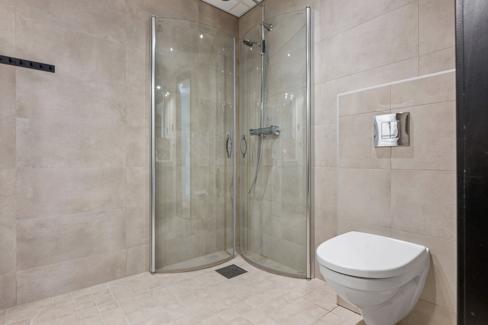 Rommet er innredet med wc på vegg, dusj på vegg med dusjvegger og opplegg for vaskemaskinog tørketrommel. Galleribilde