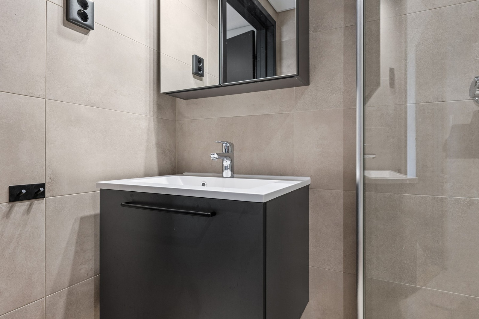 Badet er innredet med servant i servantskap, wc på vegg og dusj på vegg med dusjvegger Galleribilde