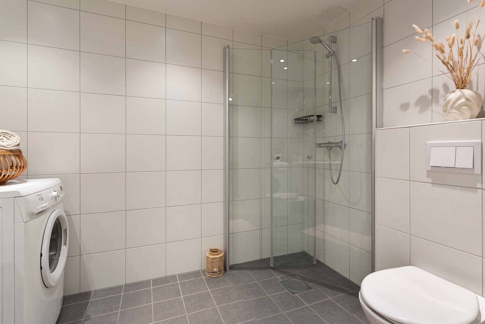 Badet er utstyrt med servant med ett-greps armatur og speil, dusjhjørne og vegghengt toalett. Galleribilde