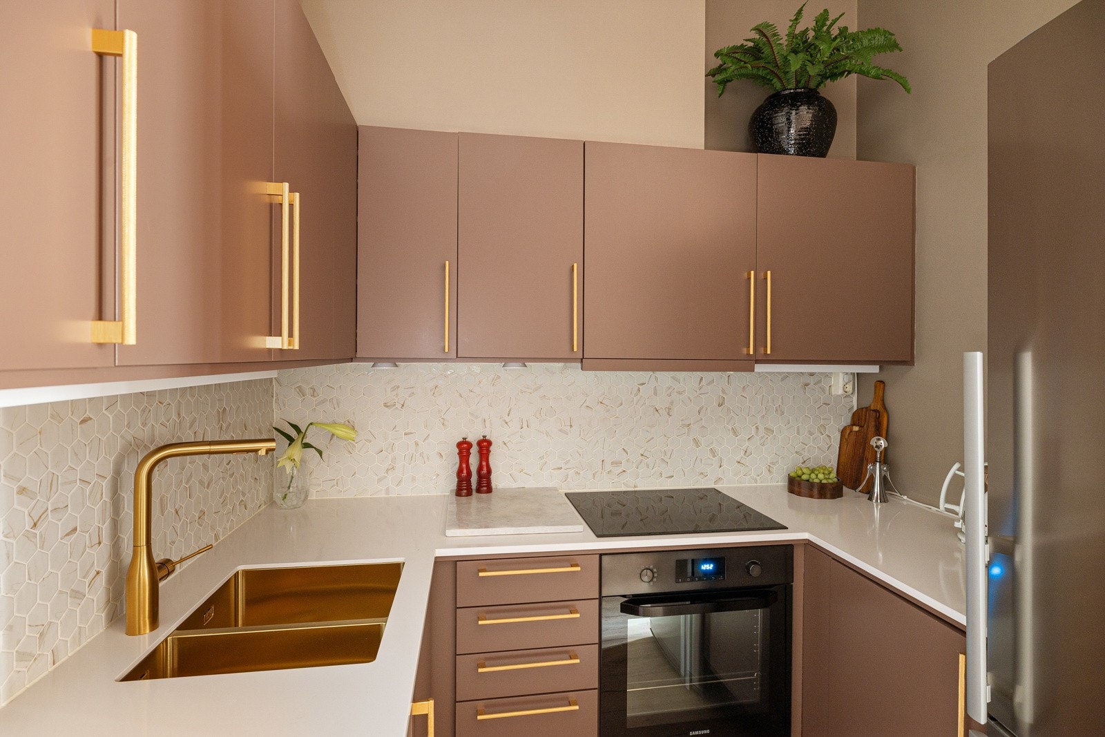 Innredningen har glatte fronter i en fin farge og påkostet benkeplate av naturstein fra 2023. Praktisk underlimt dobbel oppvaskkum og flott armatur i messing med uttrekkbar kran. Det er lekre heksagonfliser i benkeryggen og belysning under overskapene. Galleribilde