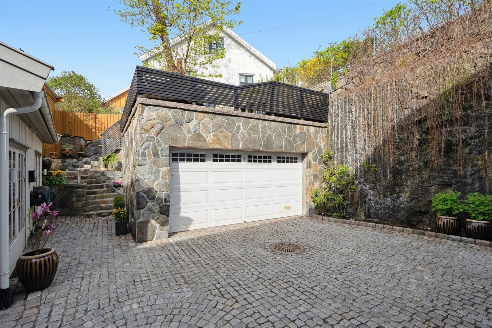 Innkjøring og gårdsplass er brostensbelagt og har stedvis up-lights lys i bakken. I bakgår er tilhørende dobbelgarasje og innredet anneks (anneks er ikke bruksendret hos kommunen) Galleribilde