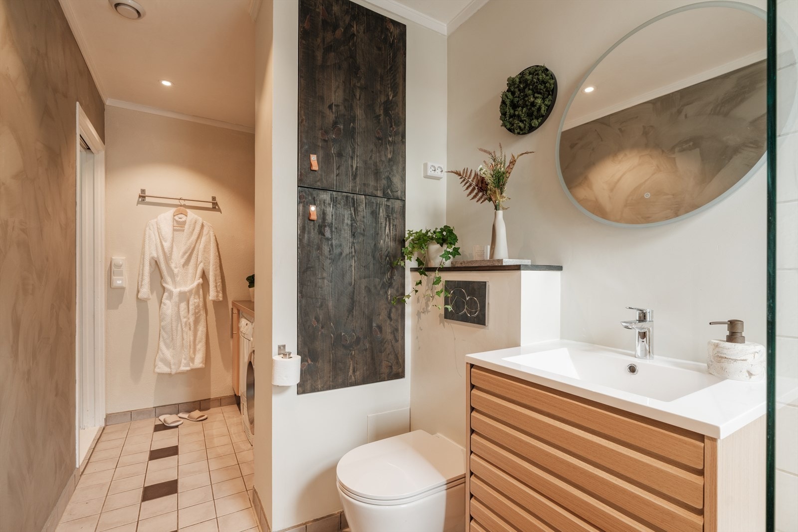 Pent og funksjonelt bad med badekar, veggmontert toalett og servantskap med ettgreps blandebatteri fra Grohe. Galleribilde