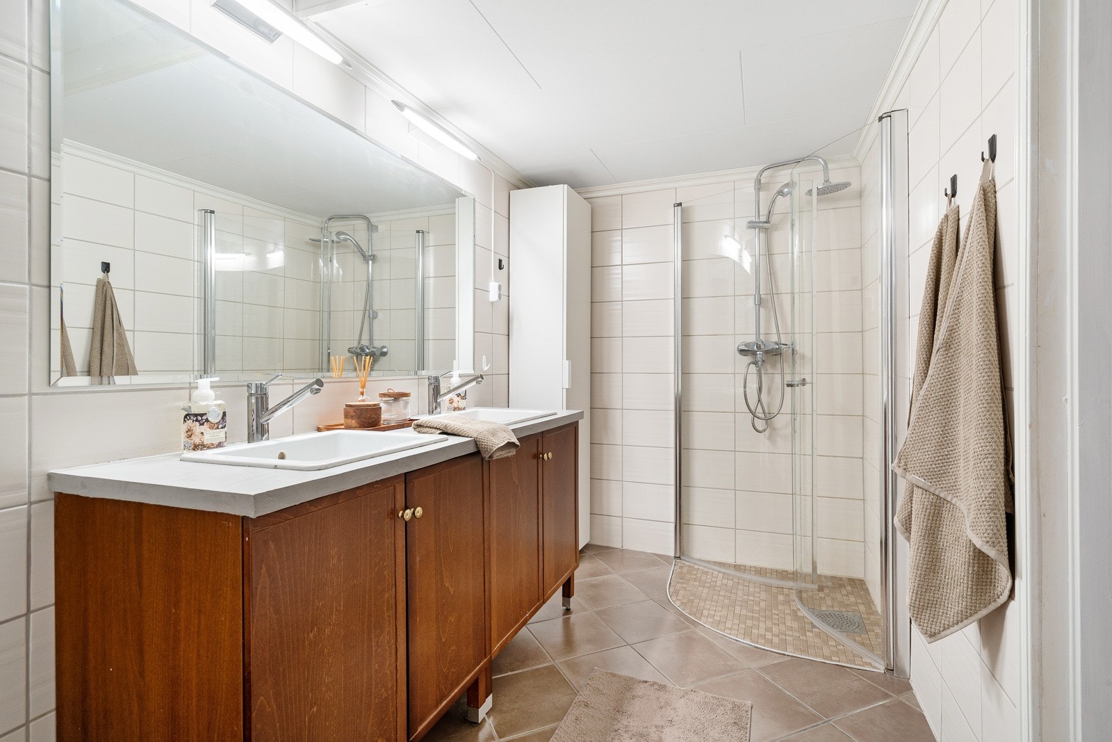 Badet er flislagt, har gulvvarme, dusjhjørne med dører og har vegghengt toalett. Galleribilde