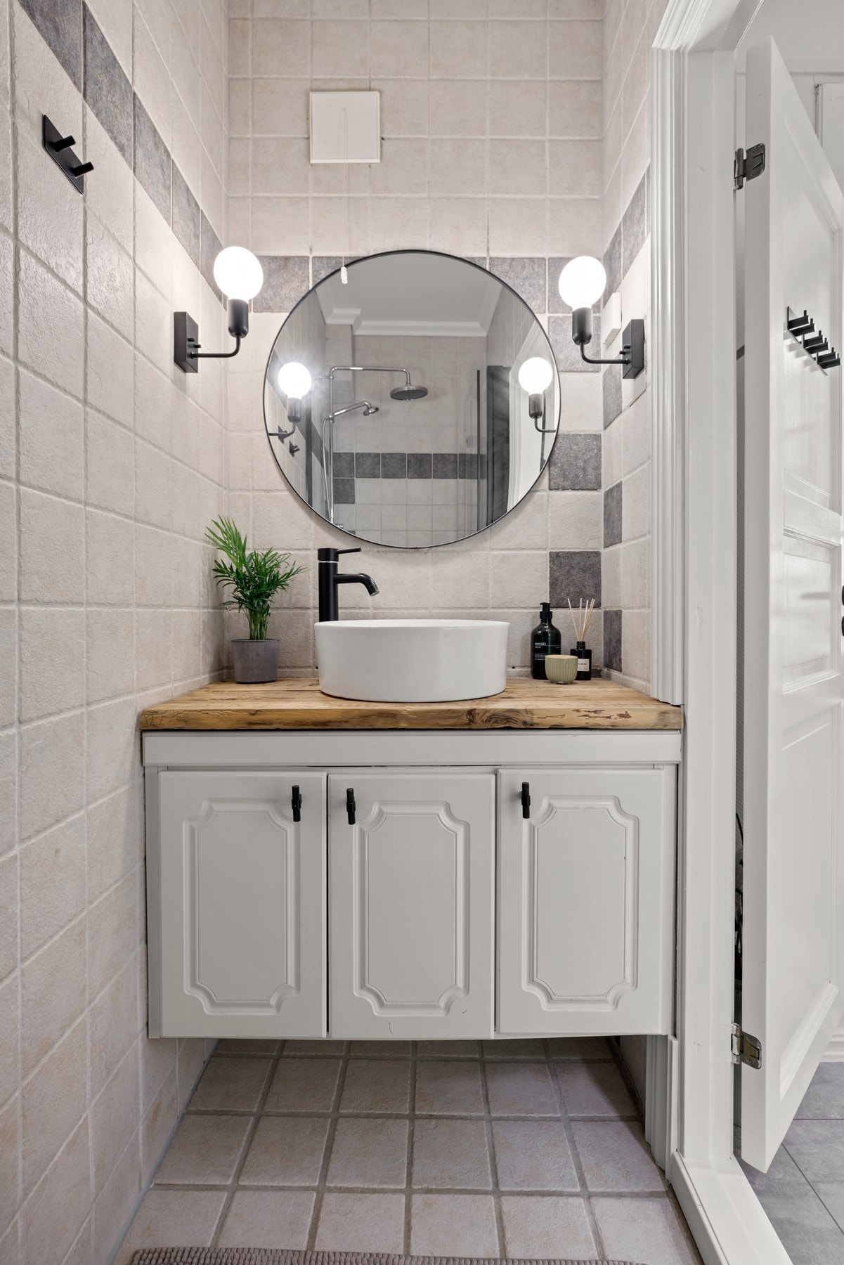 Badet har flislagte overflater og innredning med servantskap, en heltre benkeplate med servantbolle, speil og lysarmaturer. Galleribilde