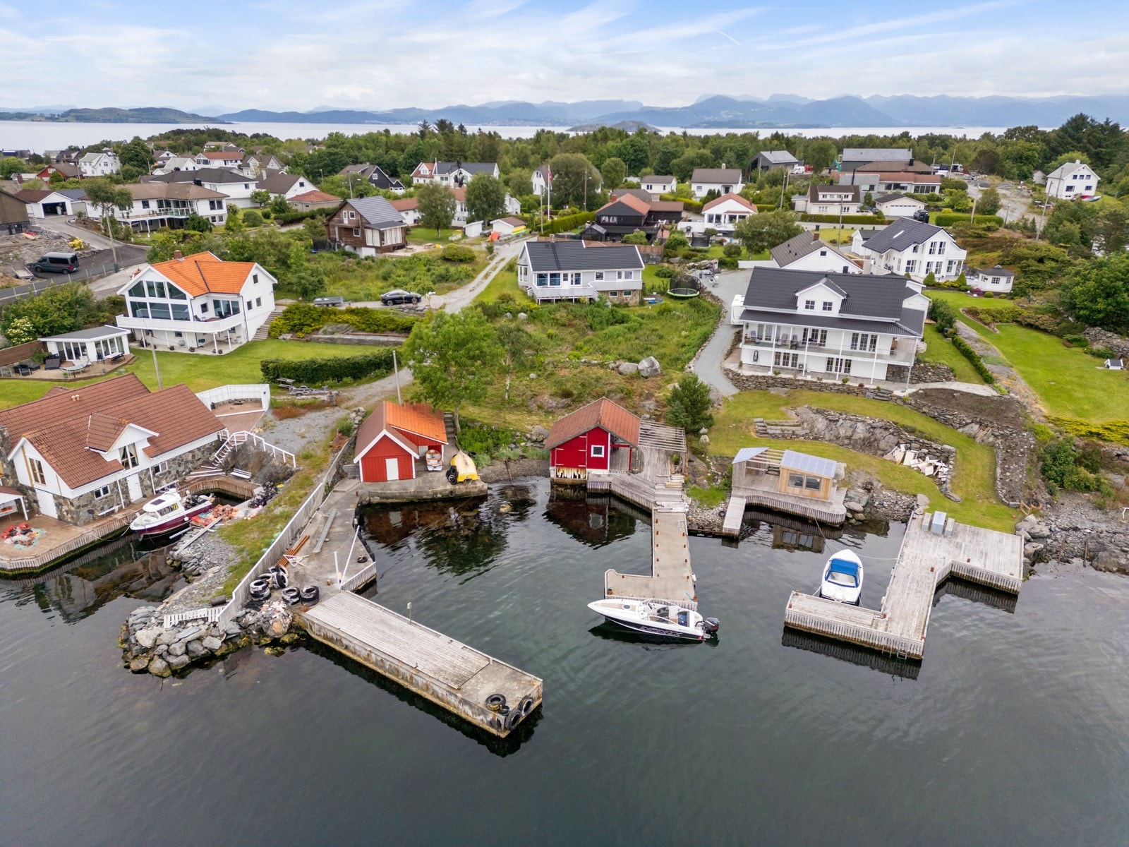 Tomten skråner ned mot sjøen og nede ved sjøen er det en stor terrasse, samt bryggeanlegg og naust. Galleribilde