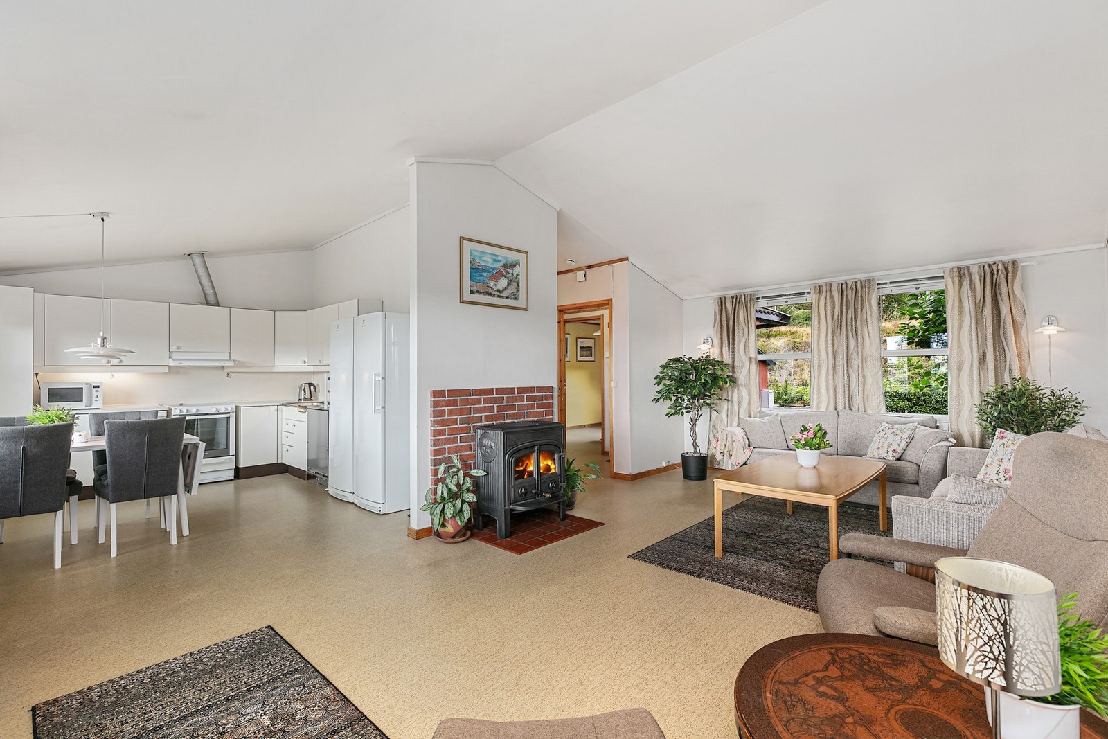 Romslig stue med peisovn og åpen kjøkkenløsning. Galleribilde