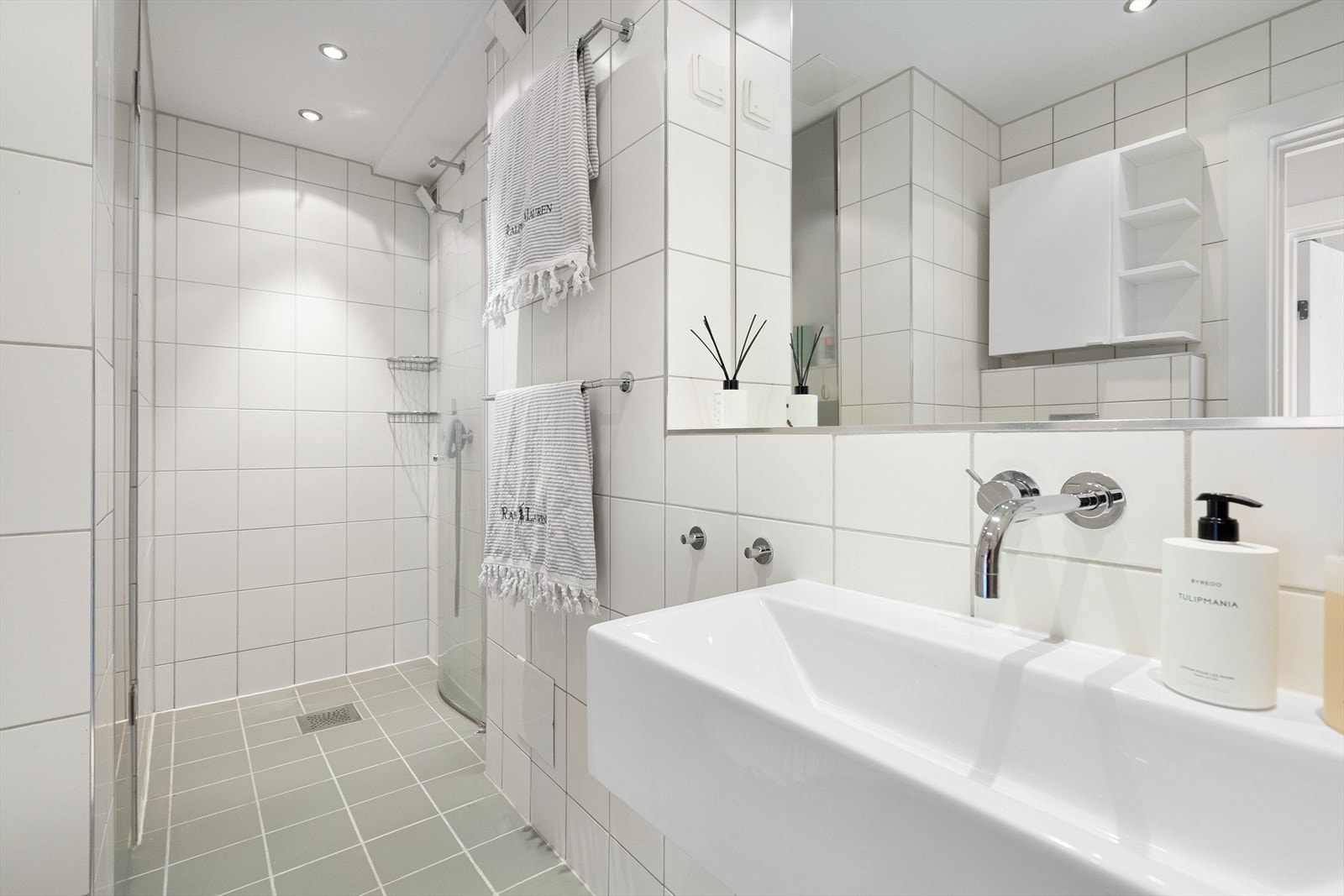 Baderomsinnredningen består av dusjhjørne med innfellbar dusjdør, veggmontert wc og servant. Servant og dusjarmatur er fra Vola. Galleribilde