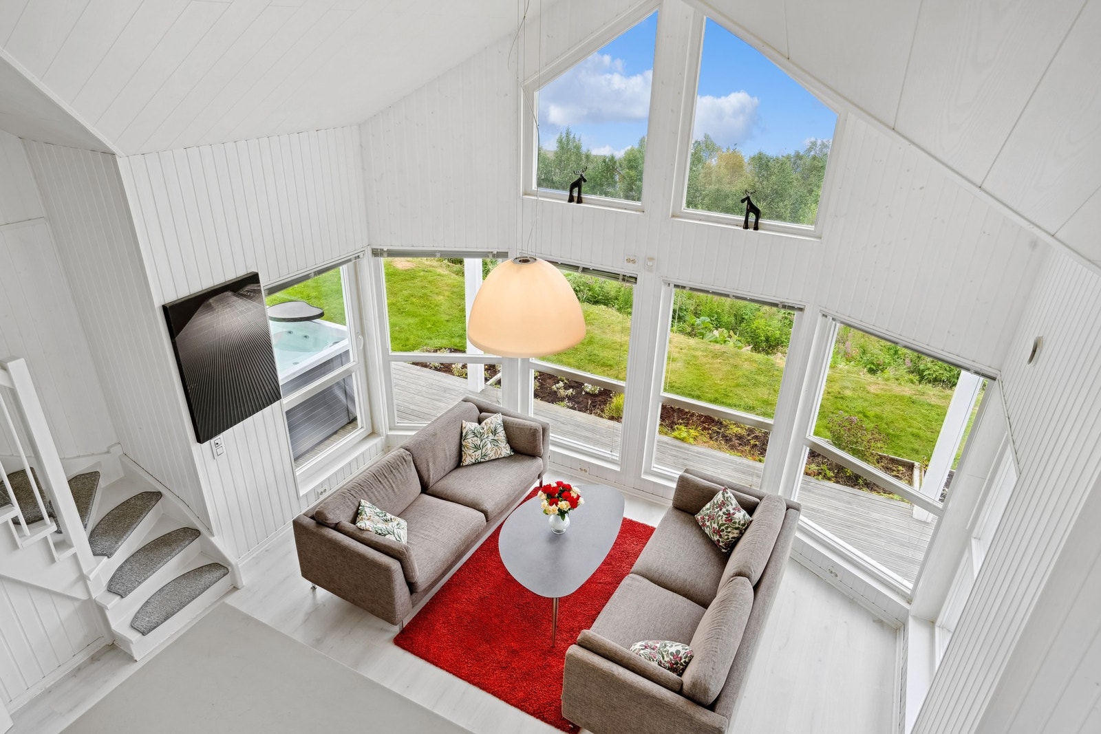 Høy himling og naturlig lys setter rammen for en romslig og innbydende stue. Galleribilde