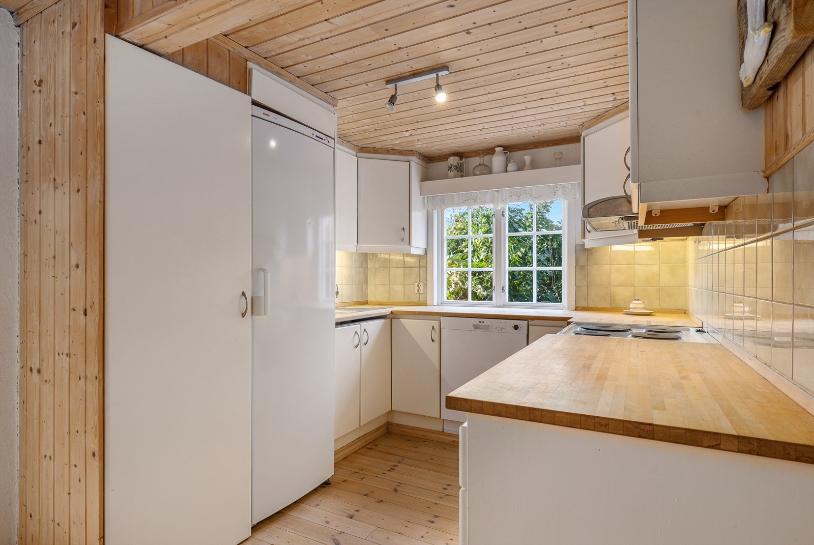 Kjøkkenet i den nordre delen har hvitmalte, glatte fronter, benkeplate i heltre og vindu over den ene benken. Galleribilde