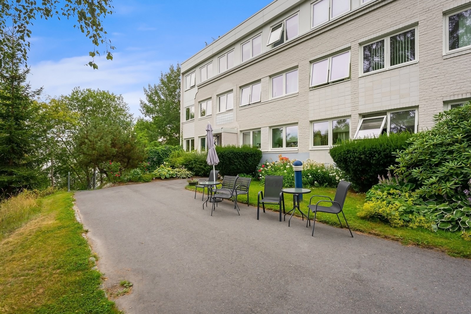 Hyggelig inngansparti med frodig beplantning og sittegrupper. Galleribilde