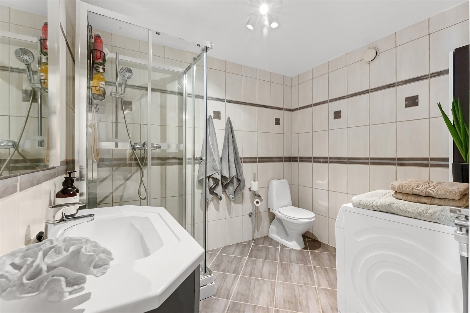 Romslig, flislagt bad med varmekabler i gulv, downlights i himling og opplegg for vaskemaskin. Galleribilde