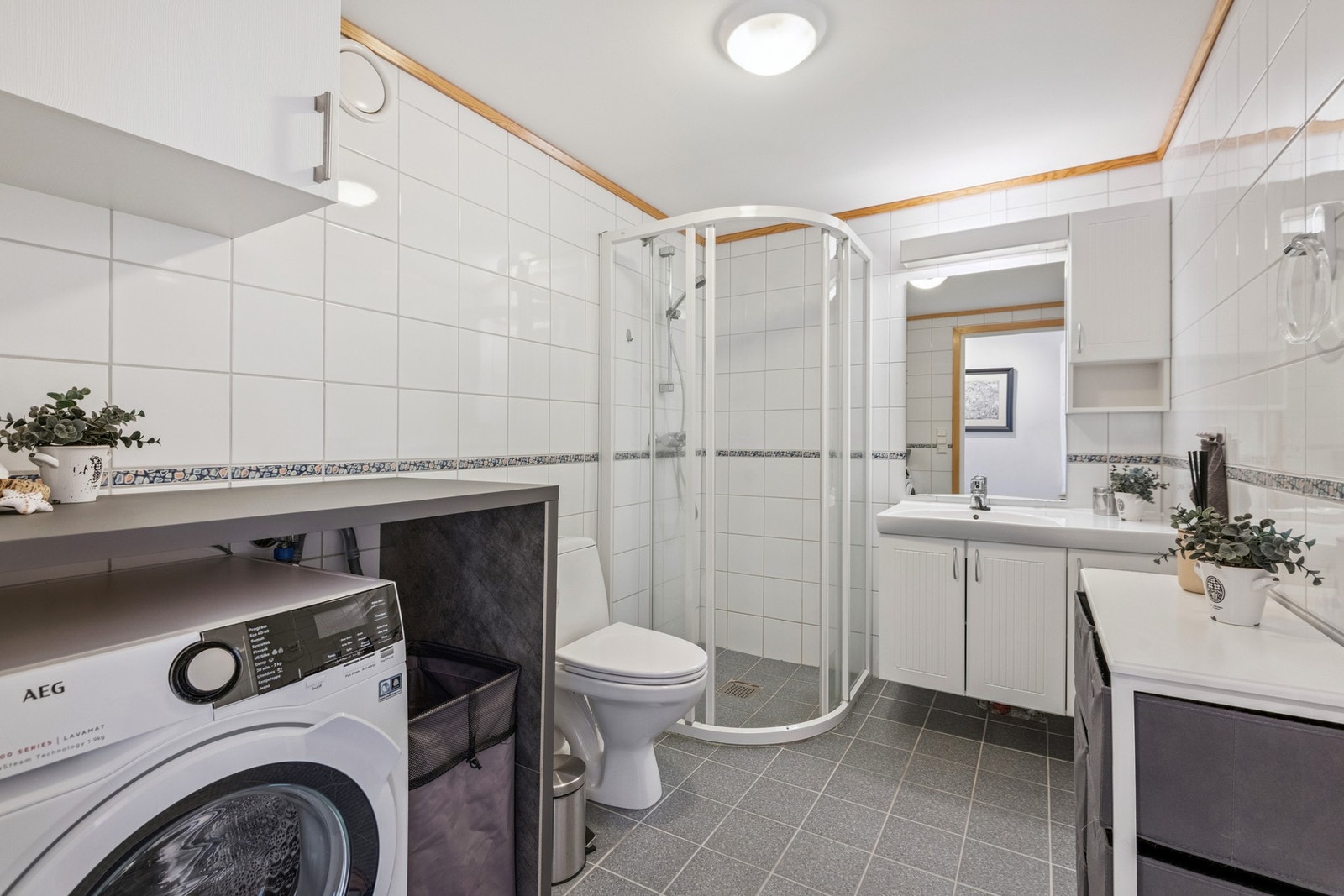 Bad med flislagte overflater, varme i gulv og dusjløsning. Opplegg for vaskemaskin med praktisk benkeløsning. Galleribilde