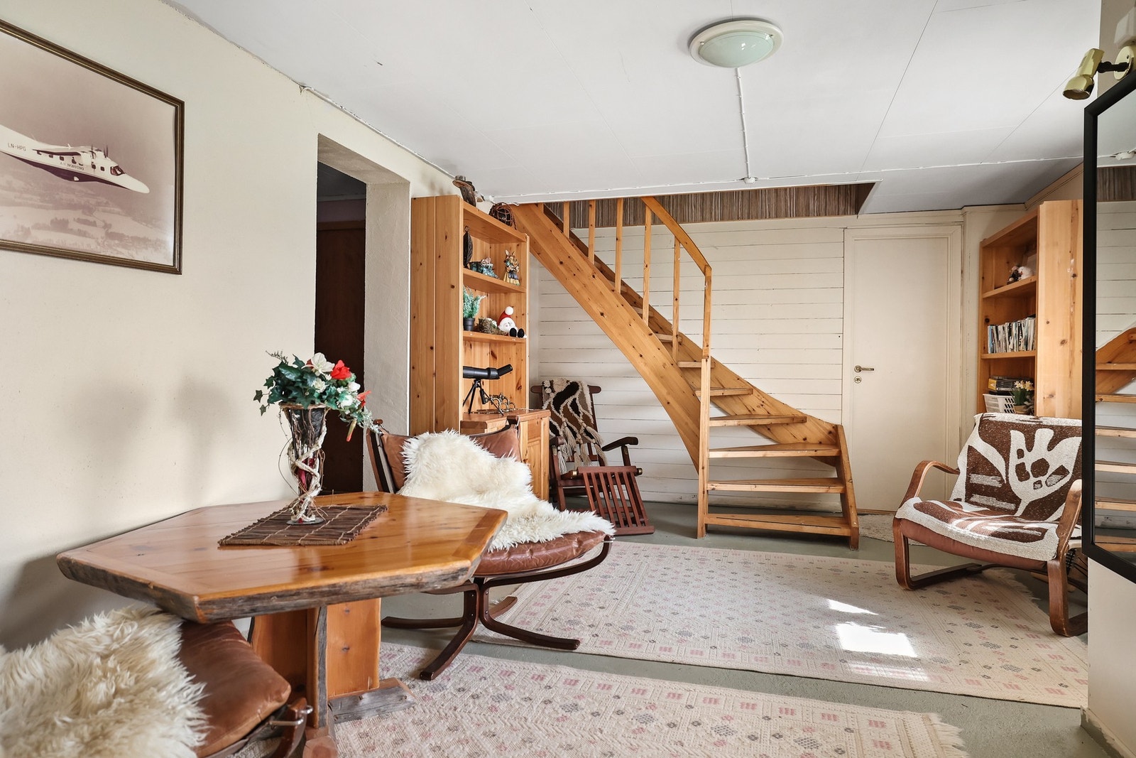 Trappen i heltre binder etasjene sammen og gir rommet et rustikt preg. Veggpanel og åpne hyller skaper en lun atmosfære med plass til både oppbevaring og personlig uttrykk. Galleribilde