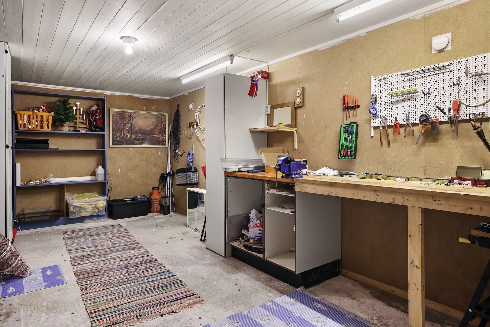 Hobbyrom med solid arbeidsbenk og god belysning. Betonggulv og enkel innredning. Galleribilde