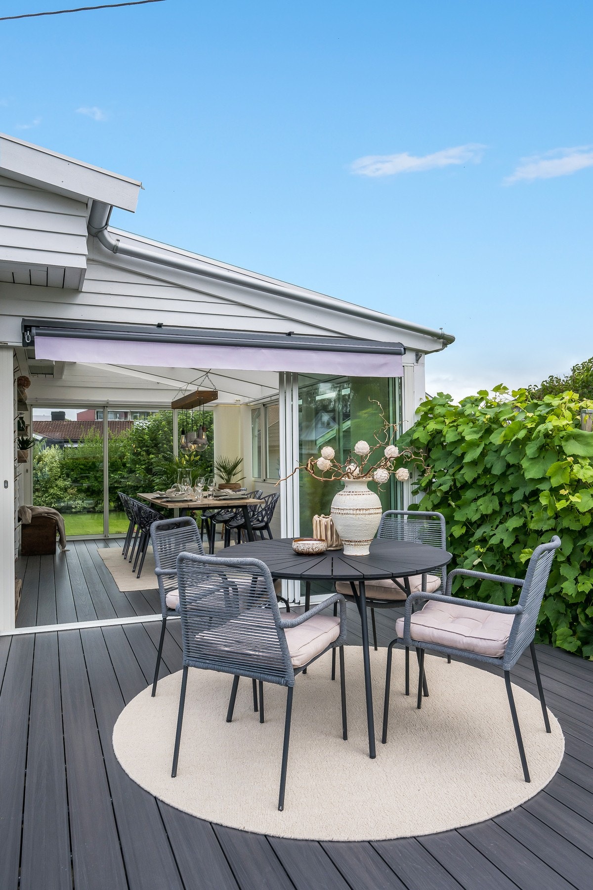 Fra vinterhagen er det dør videre ut til en solrik terrasse med markise Galleribilde