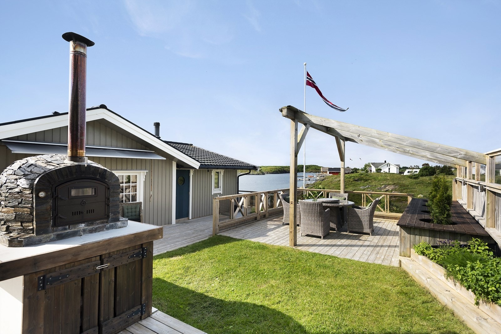 Pizzaovnen står på en platting med en levegg av store glassflater, som skjermer for vinden samtidig som utsikten kan nytes fullt ut mens maten tilberedes og serveres. Galleribilde