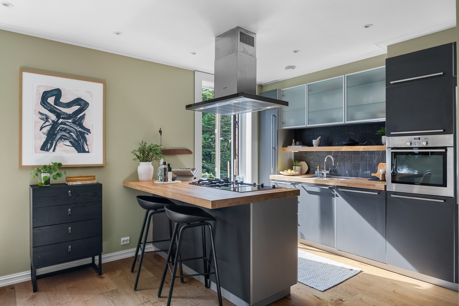 Lekkert og stilrent kjøkken med moderne løsninger og god atmosfære. Her får du rene linjer, mørke fronter, benkeplate i heltre og et flott kjøkkenøy med integrert platetopp. Galleribilde