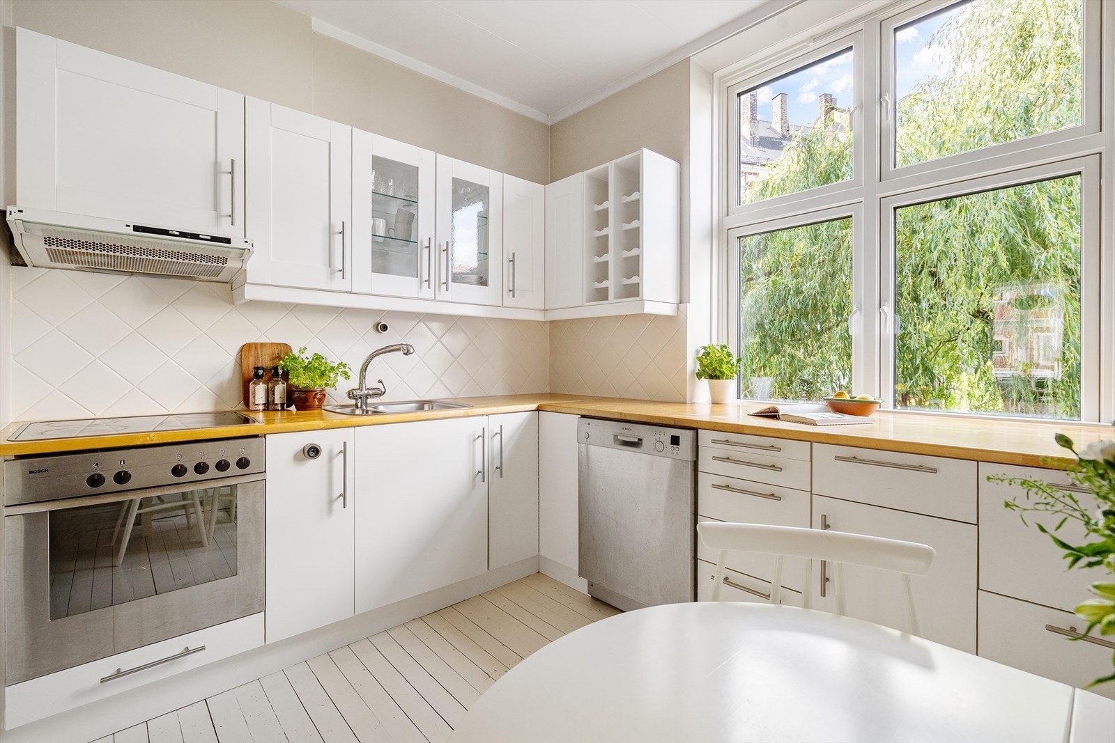 Kjøkkenet har innredning med profilerte/glatte fronter. Deler av overskapsfronter har innfelt glass og det er lysarmatur og stikk under overskap. Galleribilde