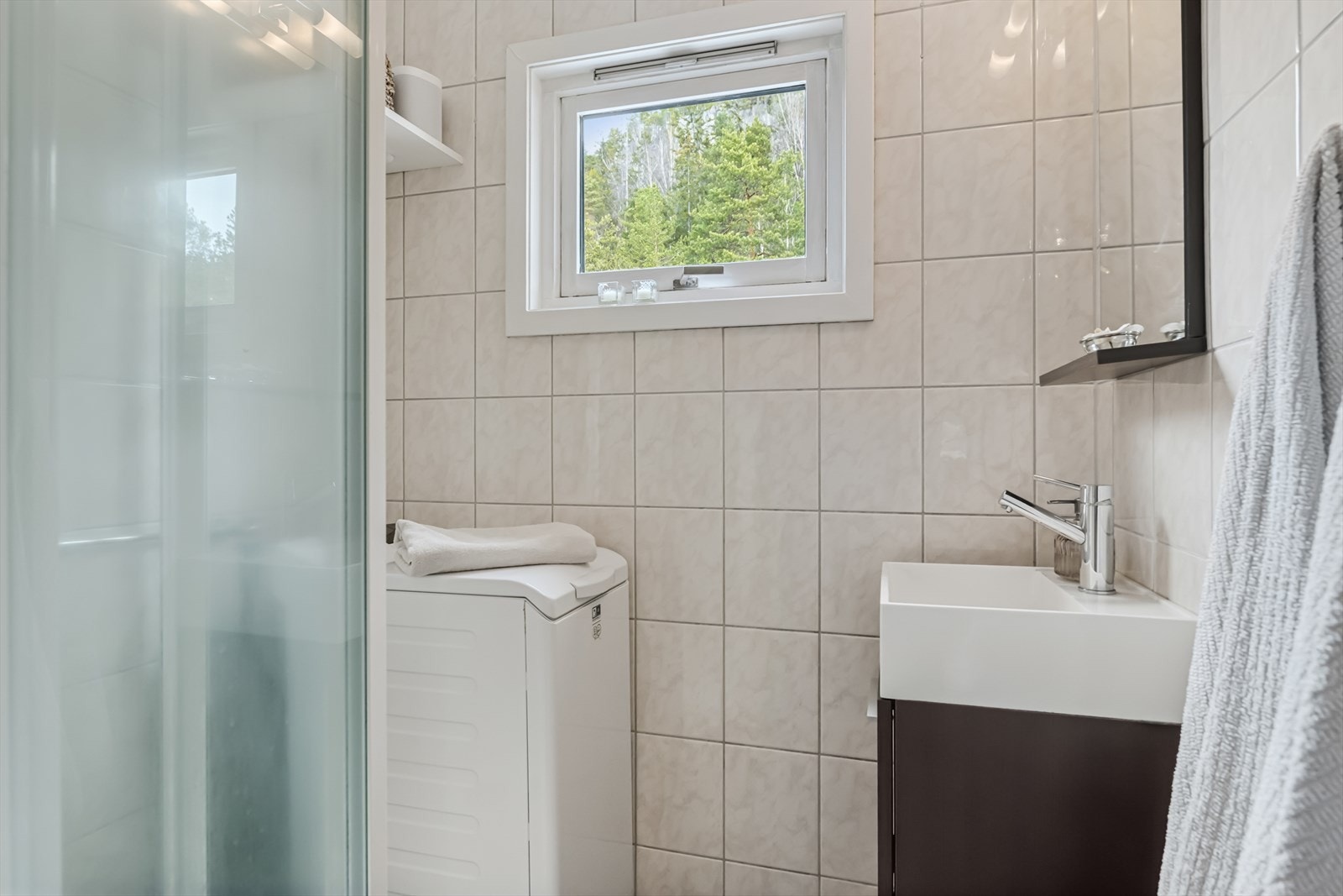 Flislagt baderom som varmes opp ved bruk av varmekabler. Rommet har innredning med nedfelt servant, dusjkabinett og opplegg for vaskemaskin. Galleribilde