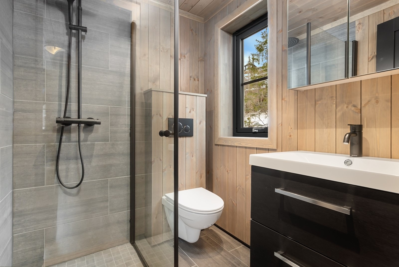 Rommet har fliselagt gulv med elektriske varmekabler og sorte detaljer gir en moderne finish. Galleribilde