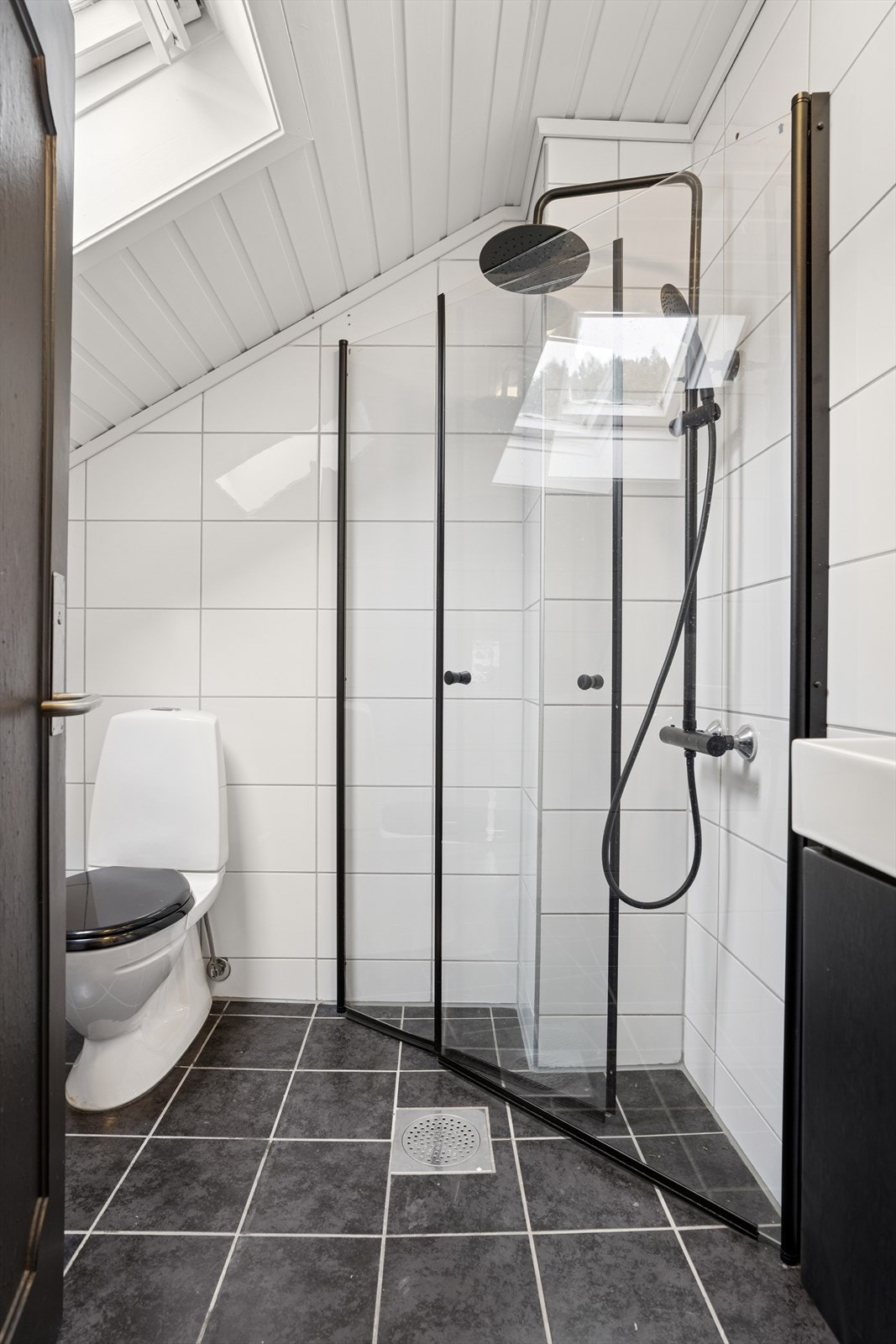 Bad/vaskerom i loftsetasje utstyrt med toalett, nedfelt servant og dusjnisje montert med tilhørende armaturer. Galleribilde