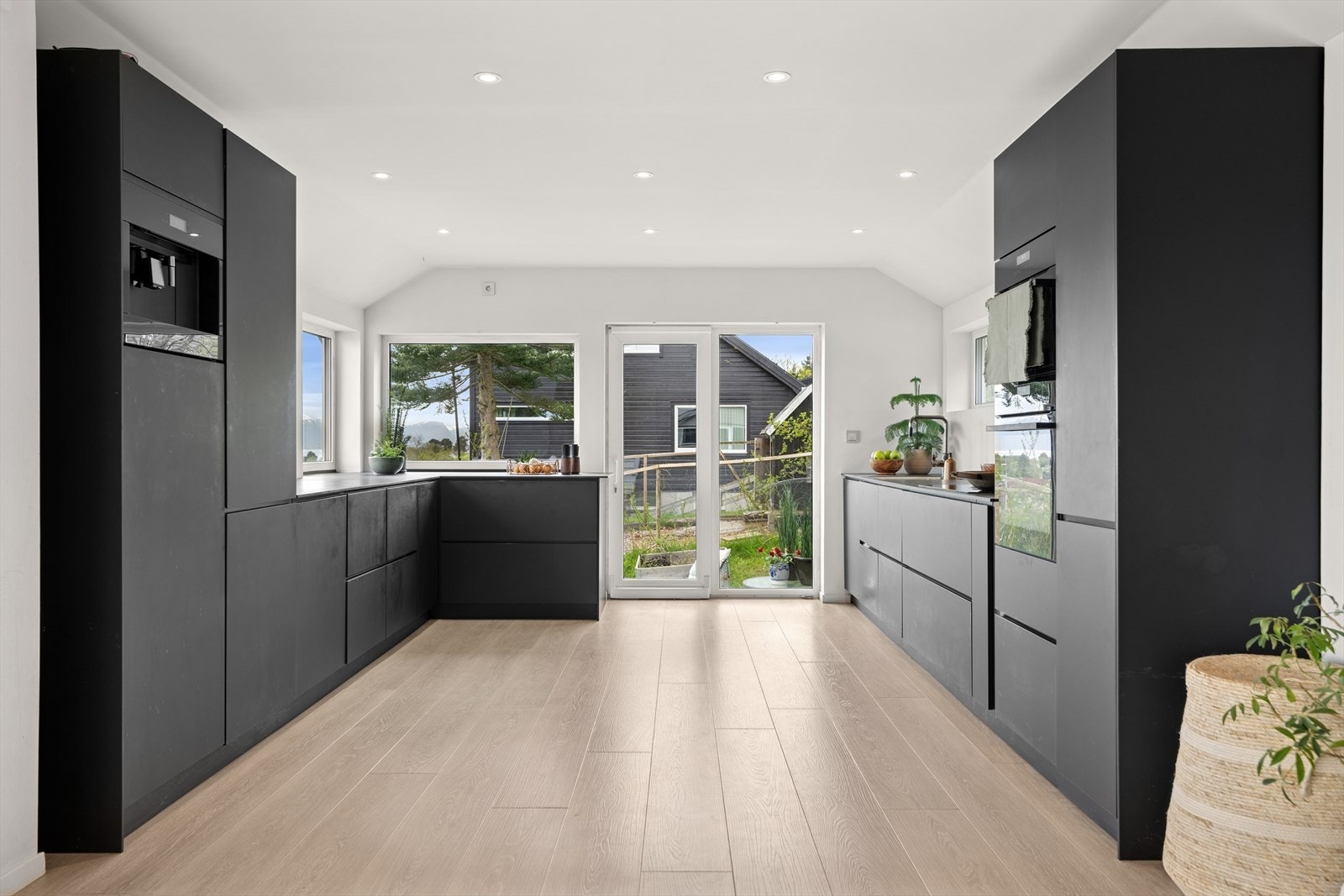 Stilren kjøkkeninnredning med malte, glatte fronter, laminat benkeplate og benkebeslag. Galleribilde