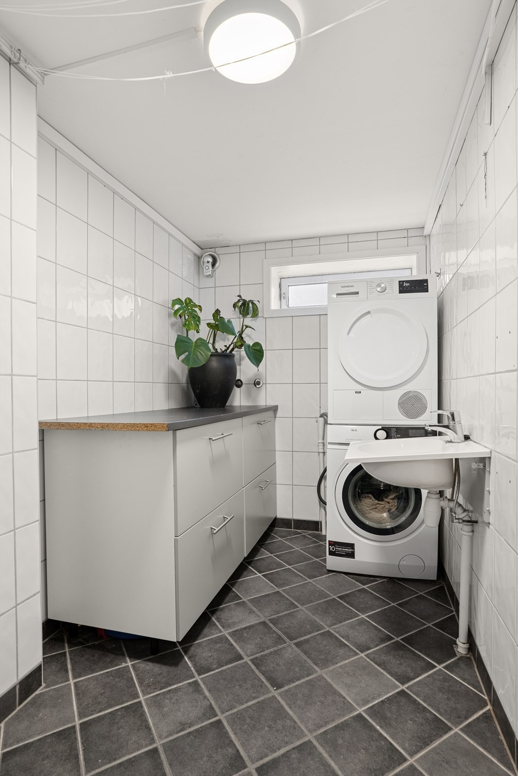 Vaskerom med opplegg for vaskemaskin. Flis på gulv med sluk og elektriske varmekabler. Rommet ble pusset opp i 2016. Galleribilde