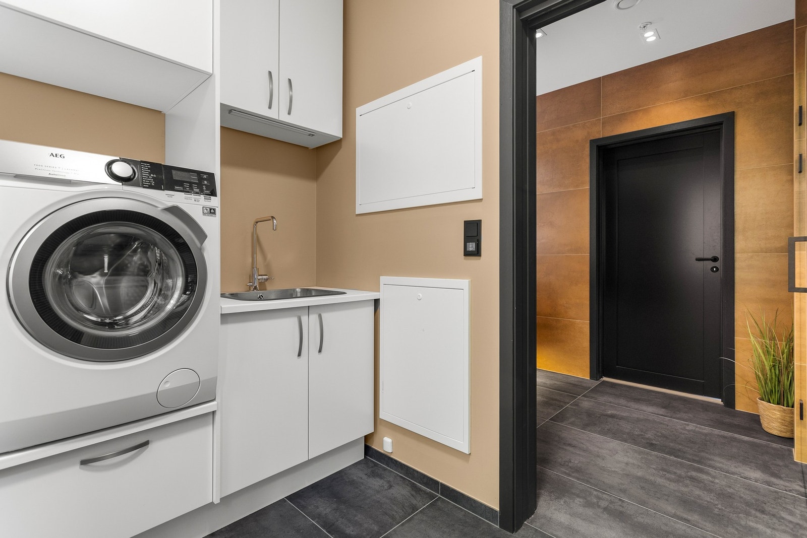 Vaskerom med god plass til vaskemaskin og tørketrommel, her er det lagringsplass med hyller og skap Galleribilde