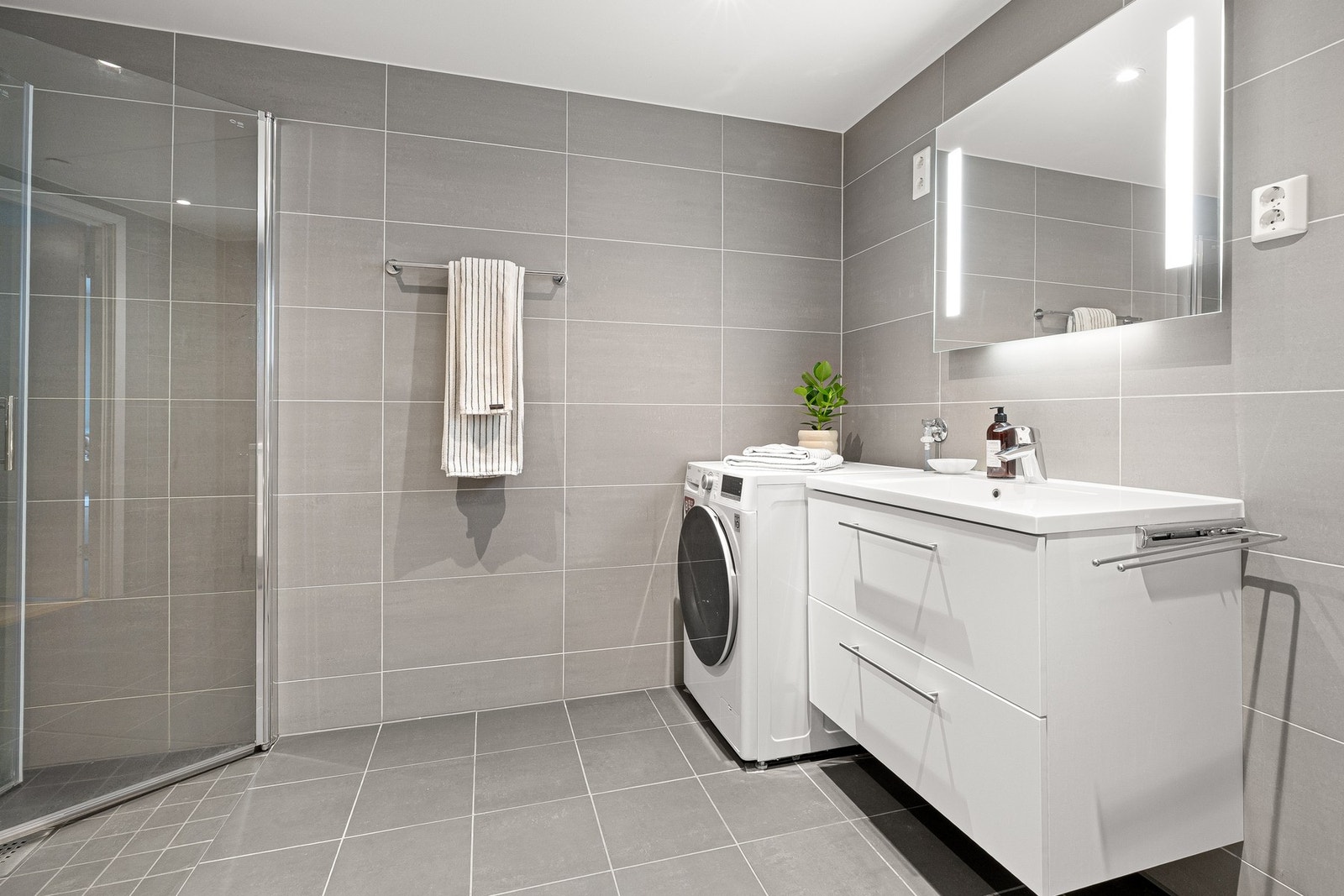 Badet har et tidløst preg med fliser i grå toner på både vegger og gulv. Galleribilde