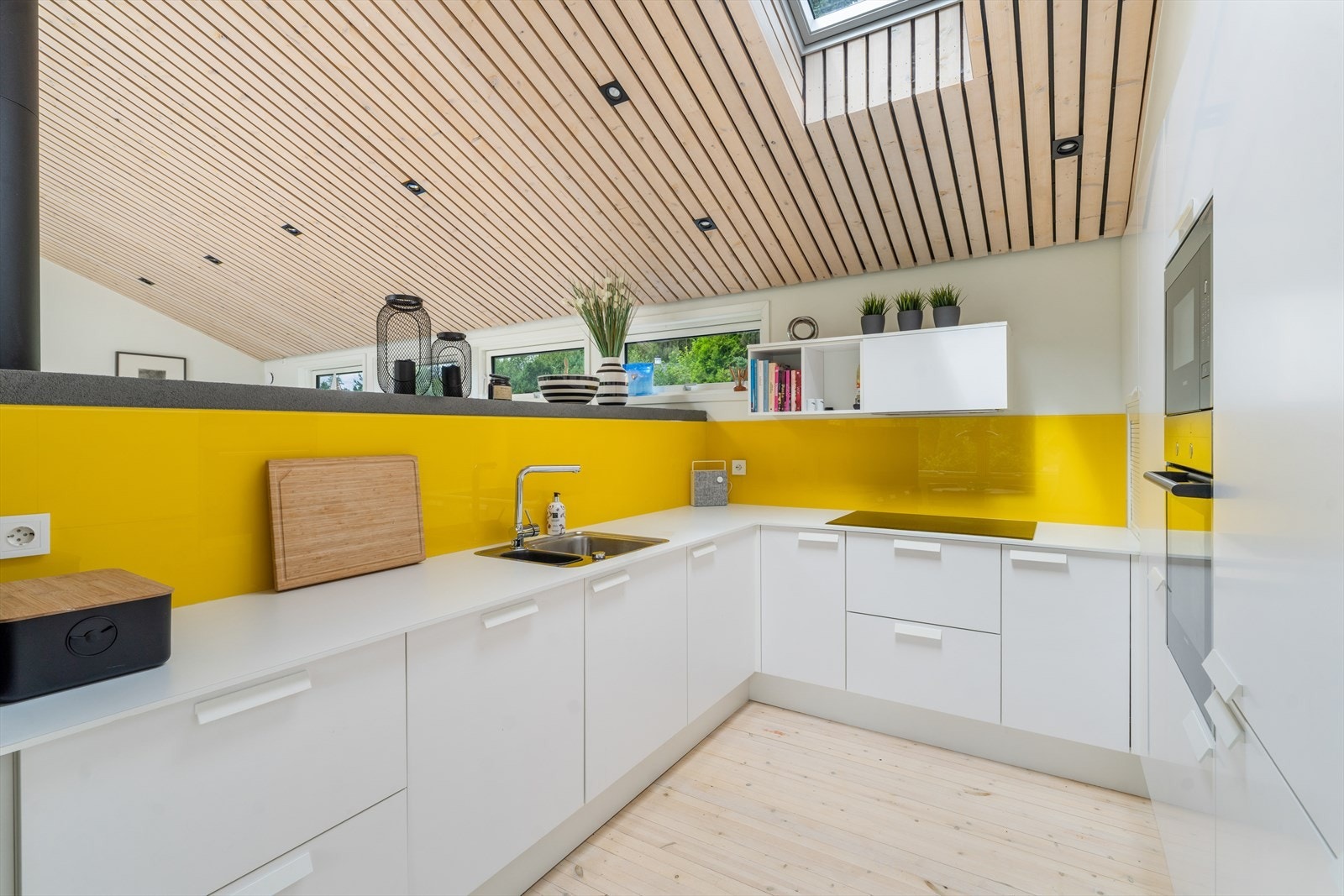 Innredningen har glatte fronter og en praktisk benkeplate i laminat, mens integrerte hvitevarer som kjøl/fryseskap, oppvaskmaskin, platetopp, mikrobølgeovn og stekeovn Galleribilde