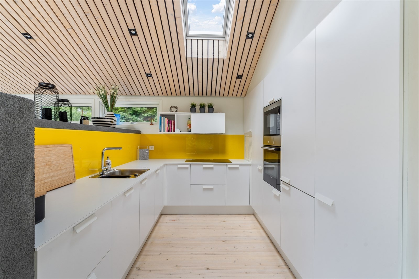 Kjøkkenet er en harmonisk balanse mellom funksjon og design, med spiler og elegante spotter i taket som skaper en lun og moderne atmosfære Galleribilde