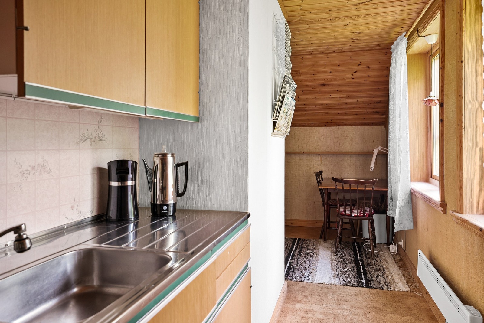 Kjøkkenbenken i stål strekker seg langs veggen, mens skråtak og panel gir kontorplassen innerst et nostalgisk preg. Galleribilde
