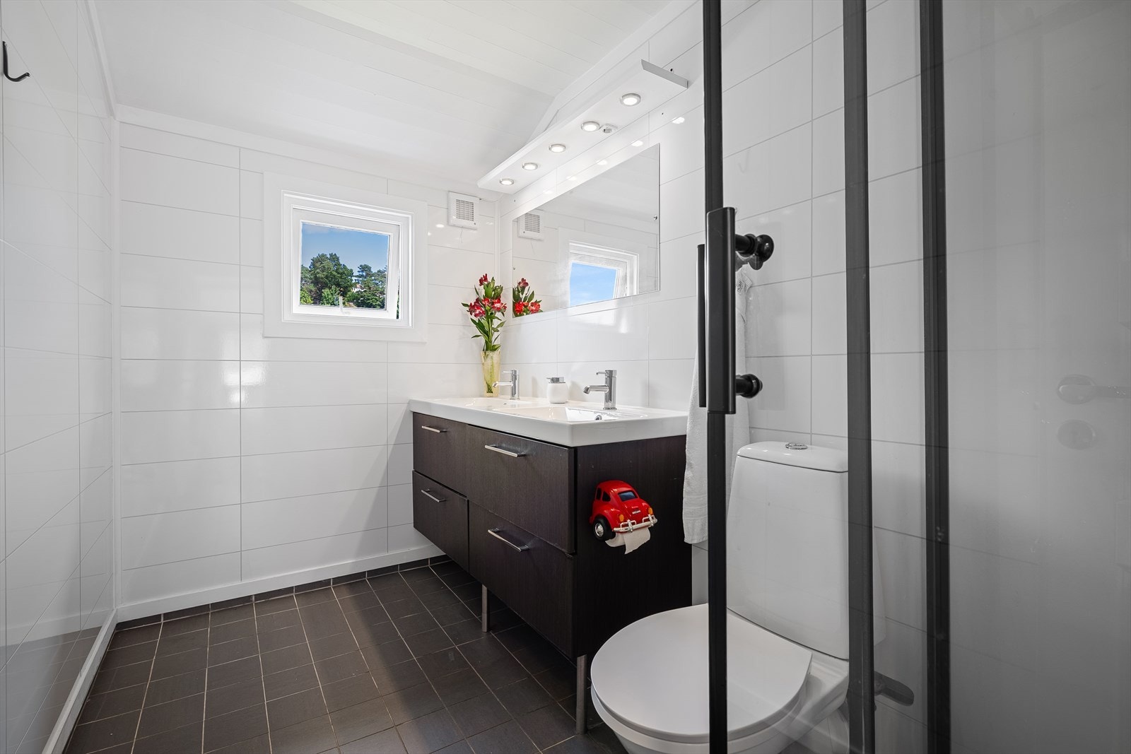 Badet i 2.etg. har fliser på gulvet med varmekabler, samt våtromsplater på veggene. Det inneholder en baderomsinnredning med dobbel vask, toalett, samt et praktisk dusjkabinett. Galleribilde