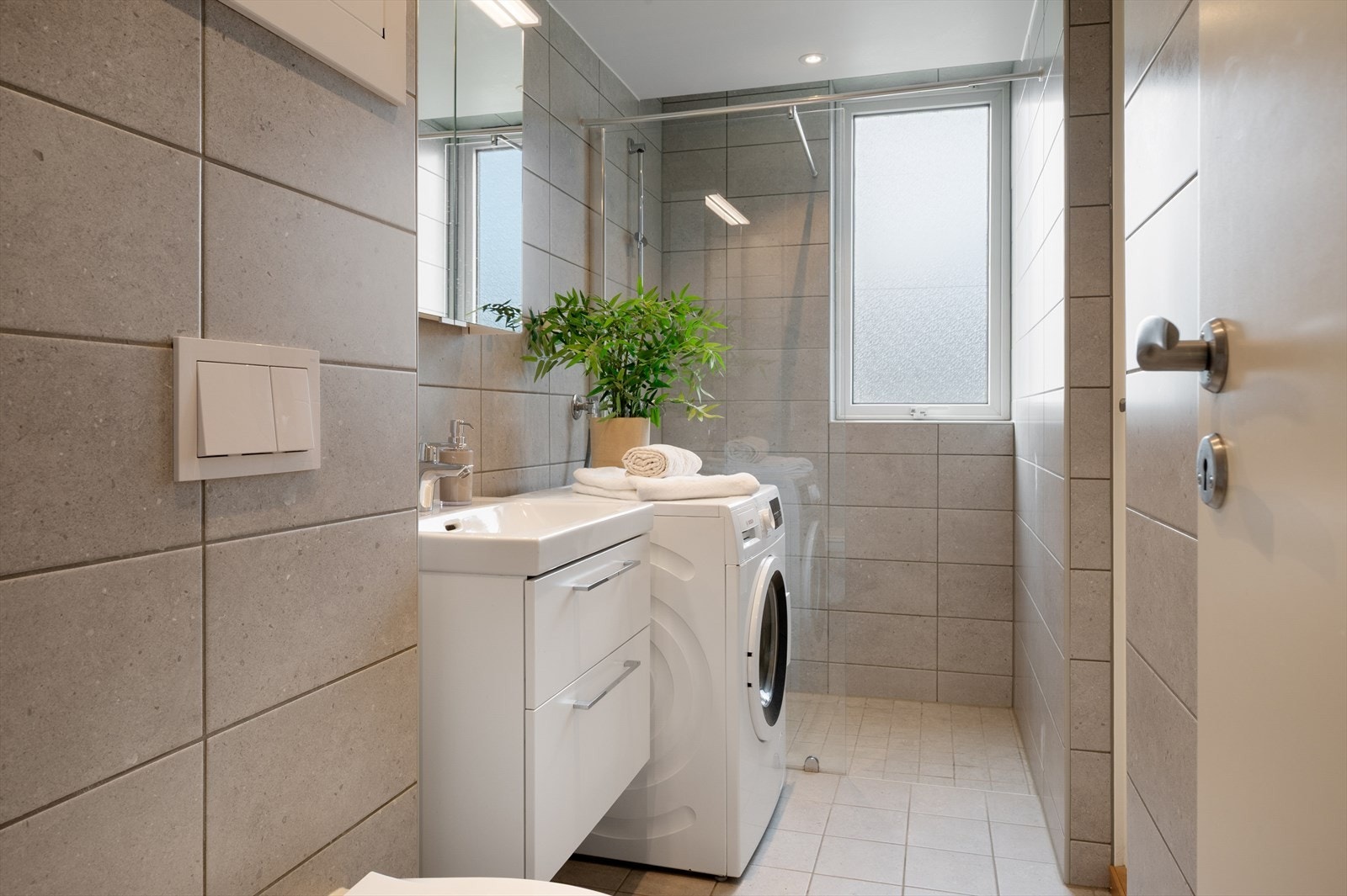 - Badet inneholder servant med møblement, speilskap med belysning, vegghengt toalett, dusj, opplegg for vaskemaskin og rør i rør skap - Galleribilde