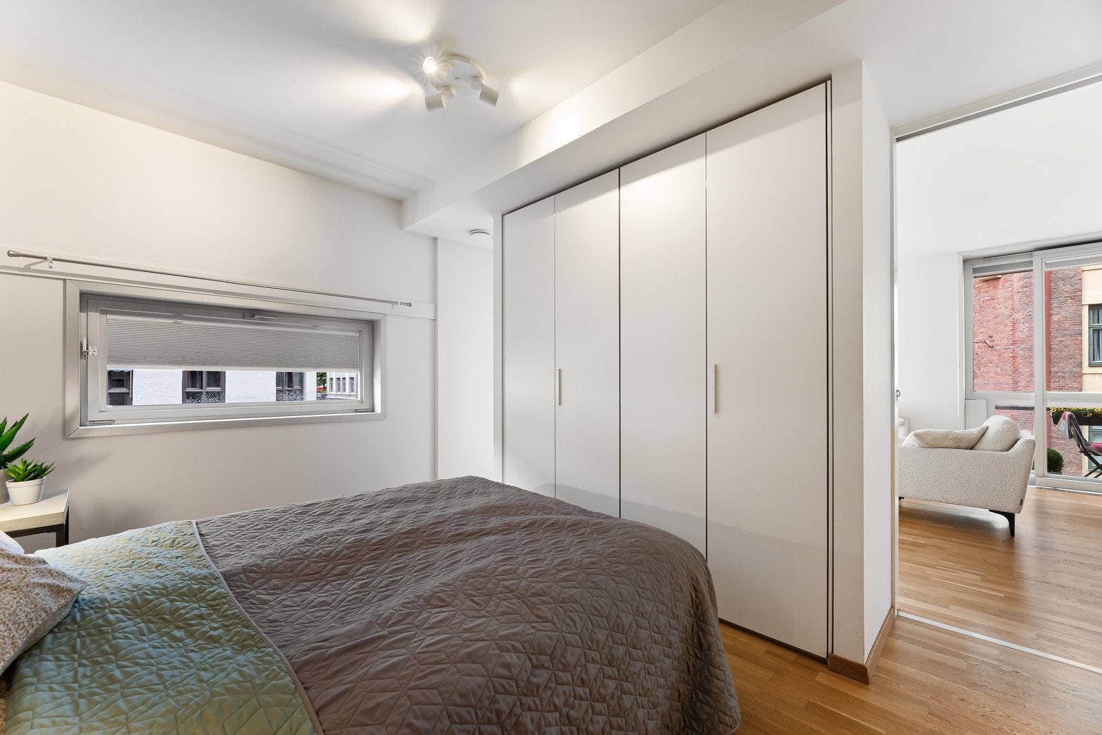 Langs veggen mellom dørene er det montert hvite garderobeskap som gir rikelig med skapplass. Galleribilde