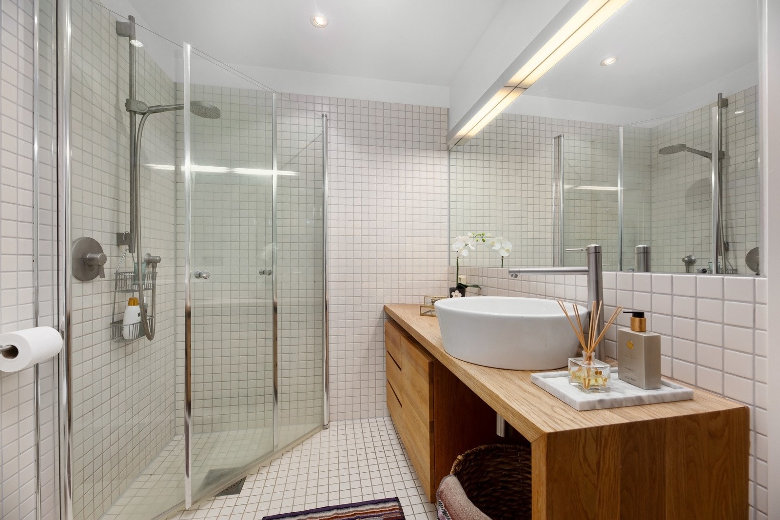 Badet har veggmontert toalett og et dusjhjørne med innfellbare glassvegger. Leiligheten er tilknyttet felles varmtvann for bygget. Galleribilde