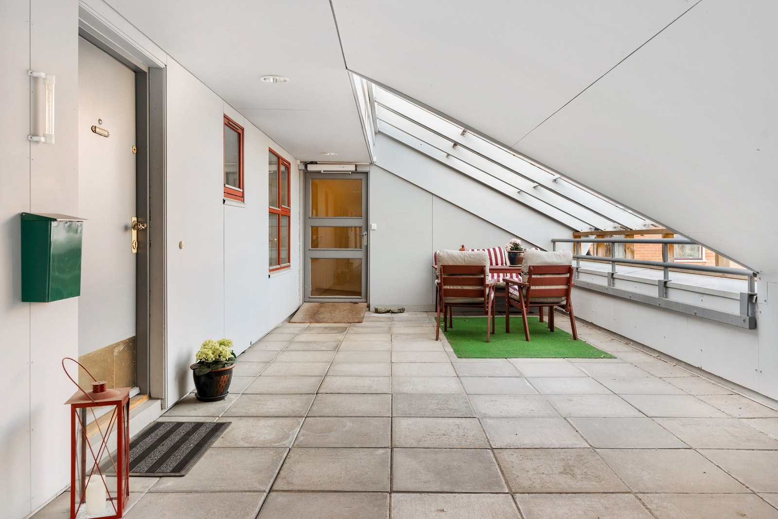 Innglasset terrasse ved inngangspartiet til leiligheten. Her disponerer leiligheten området utenfor egen leilighet til å plassere utemøbler. Inngangsdøren til venstre i bildet Galleribilde