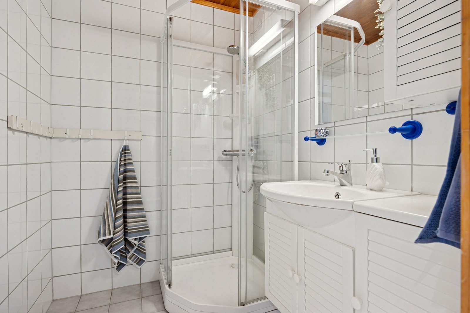 Badet er flislagt og innredet med dusjkabinett (nytt i 2021), servantskap og servant. Galleribilde