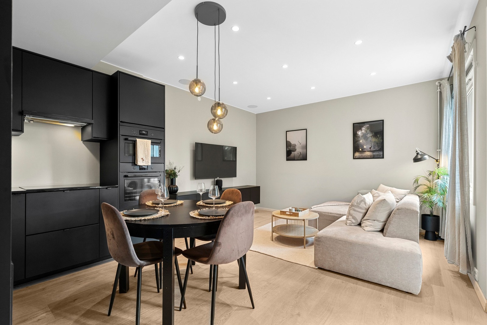 Åpen stuen- kjøkkenløsning med moderne innredning, spiseplass og sofahjørne. Store vinduer gir godt med naturlig lys. Galleribilde