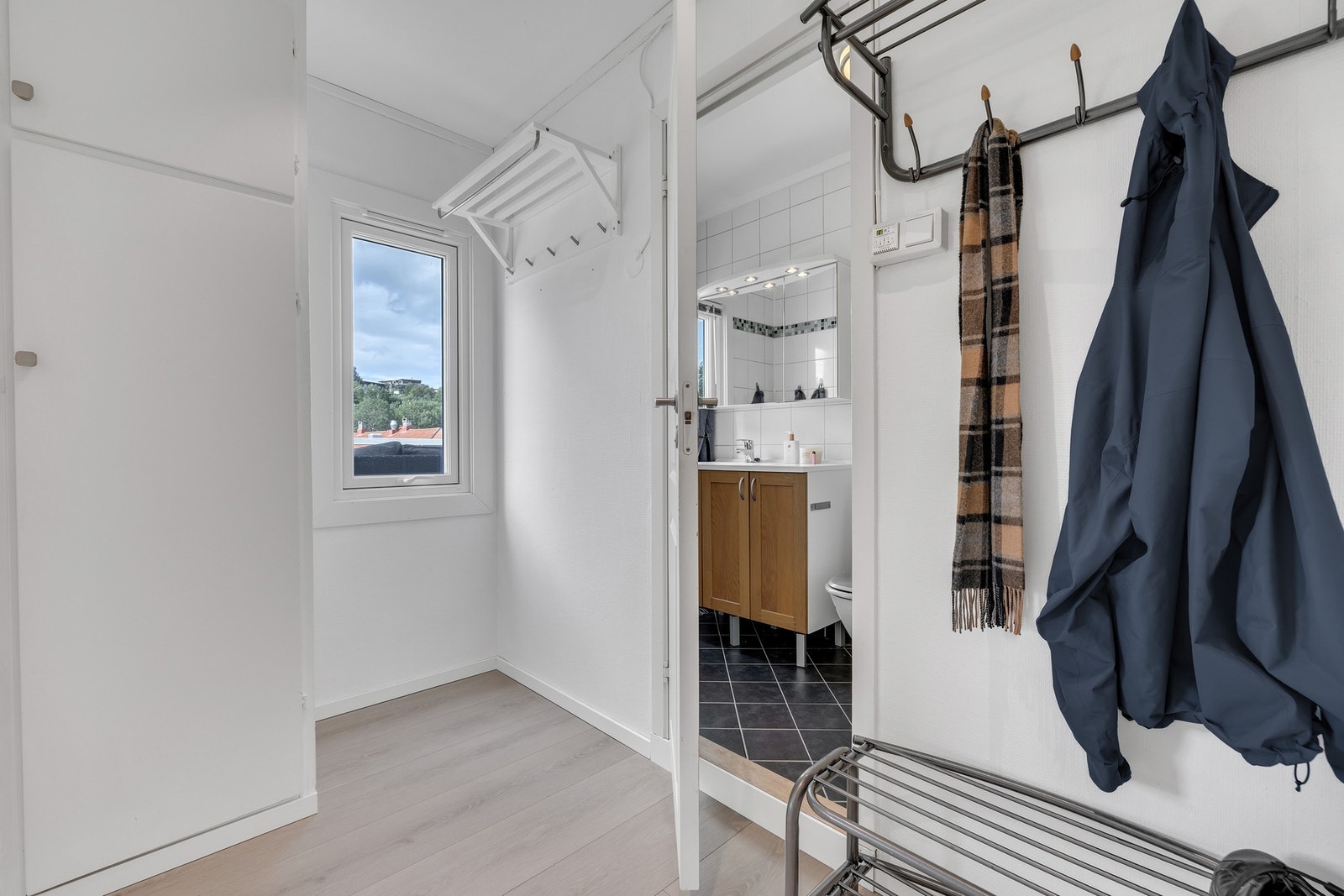Lys og fin entré med enkel klesoppheng og oppbevaring i innebygd garderobeskap. Galleribilde