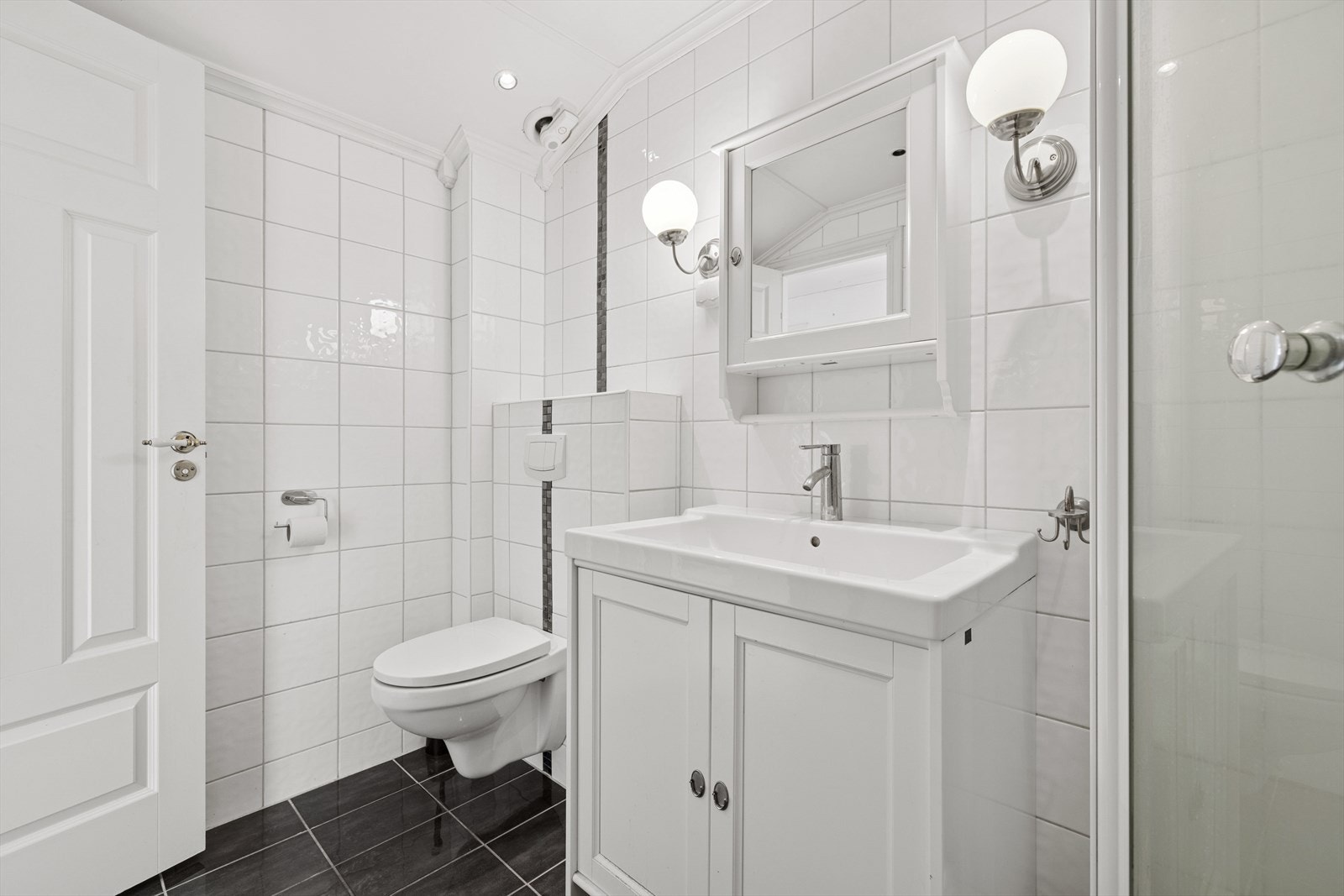 Innredningen består av speilskap, servant med seksjon, veggmontert toalett og dusjkabinett. Galleribilde