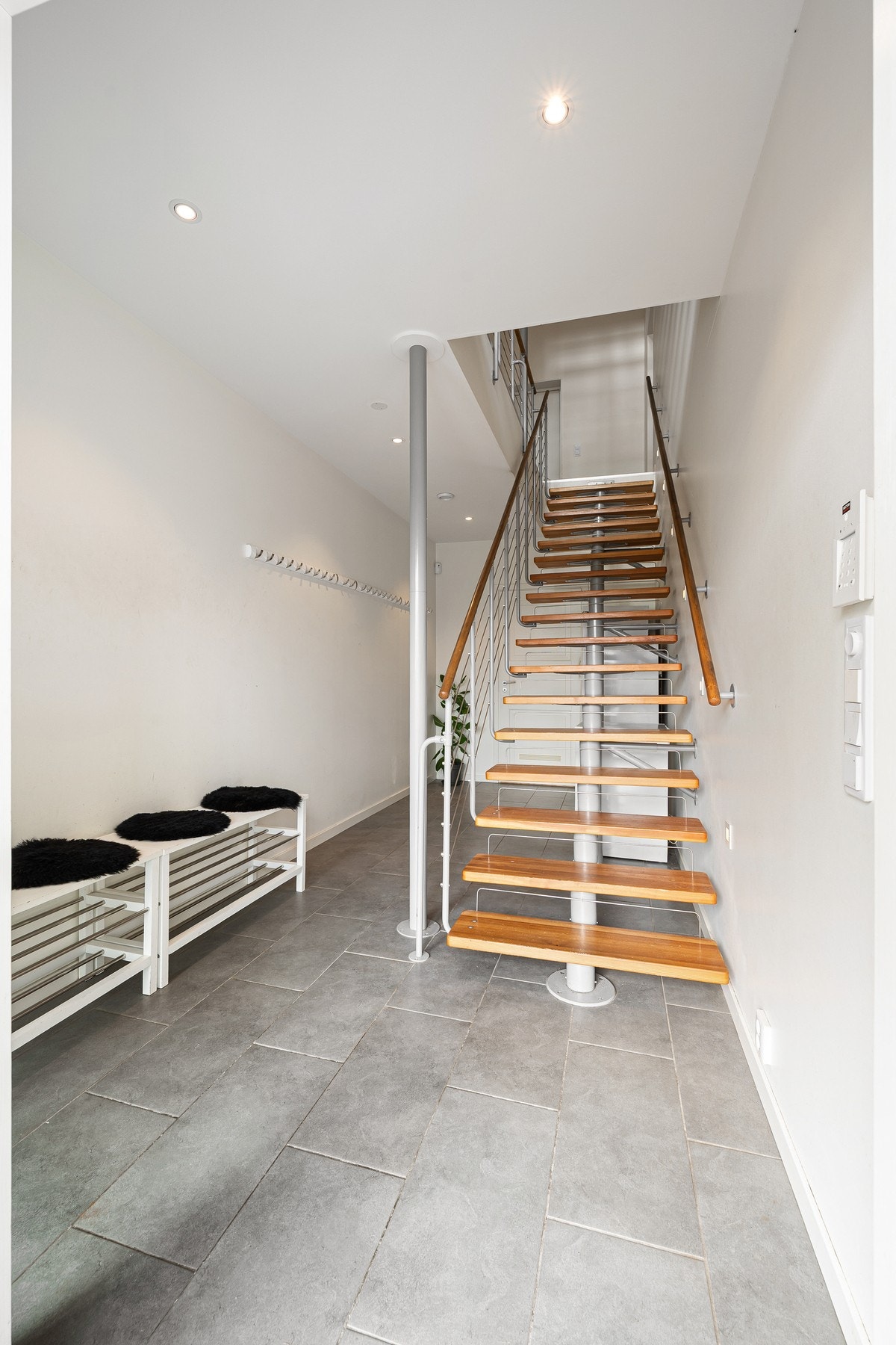 Entré/hall har flislagt gulv og rikelig med plass til oppheng av yttertøy, samt plass til garderobeskap bak trapp Galleribilde