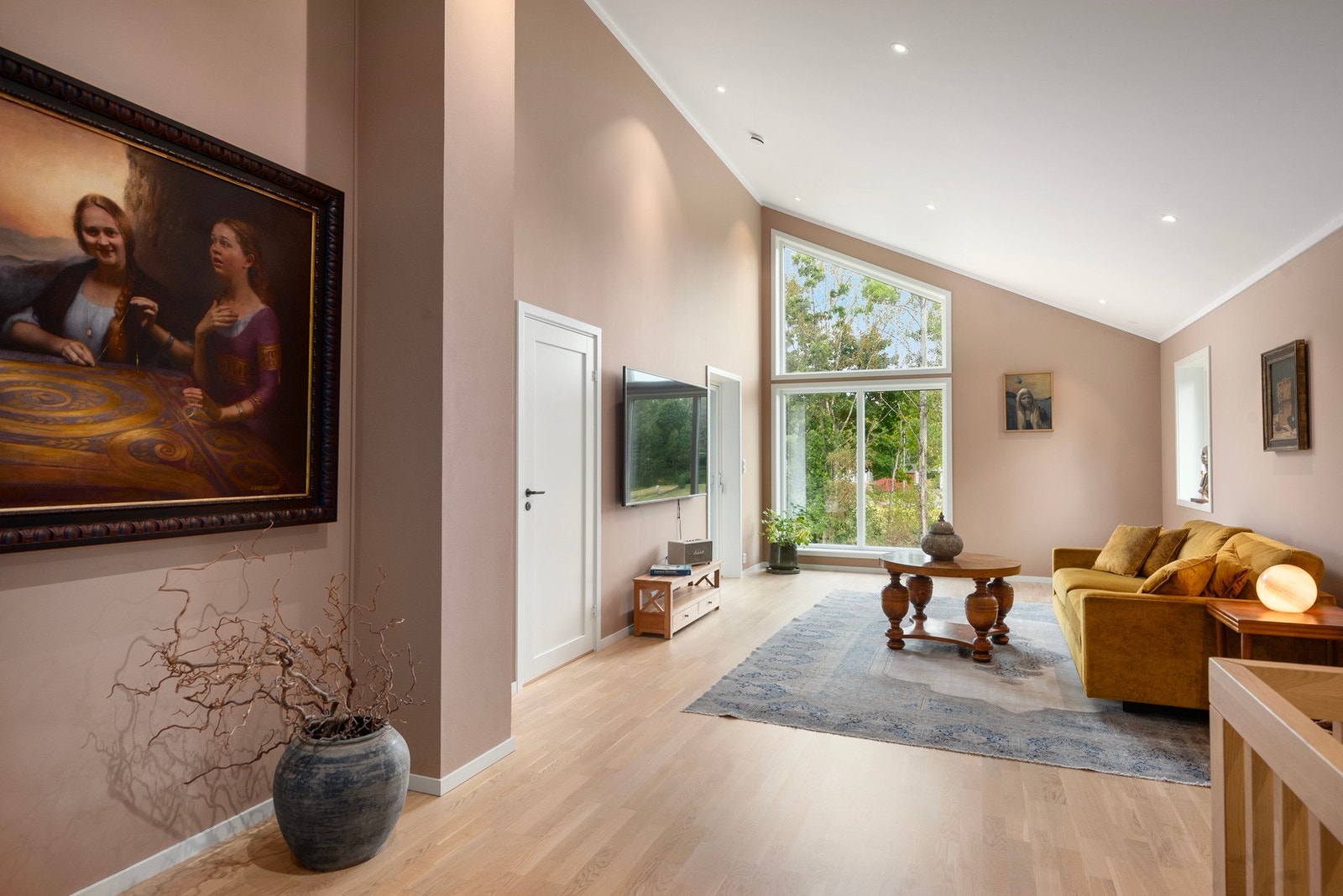 Opp trappen er det en lys stue med store vindusflater og høyt under taket. Galleribilde