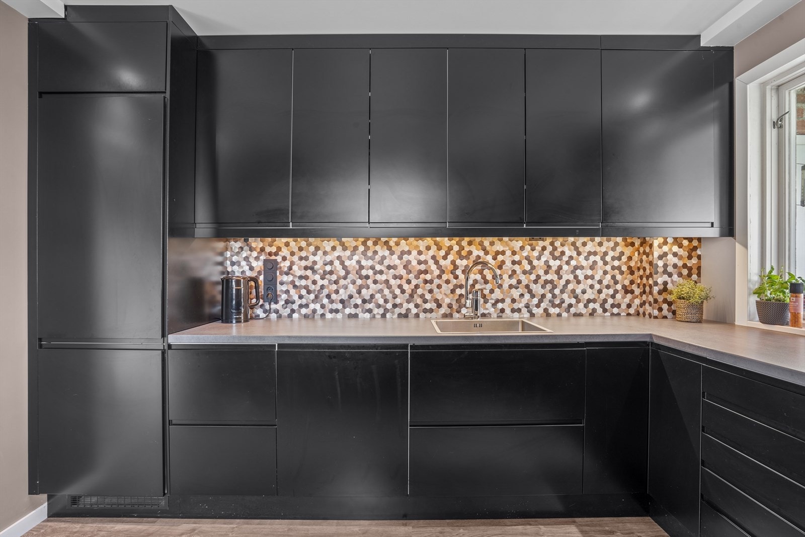 Kjøkkeninnredning er av nyere dato og har laminerte slette fronter i mørk farge, laminert benkeplate med nedfelt oppvaskkum i stål med ett-greps blandebatteri. Galleribilde