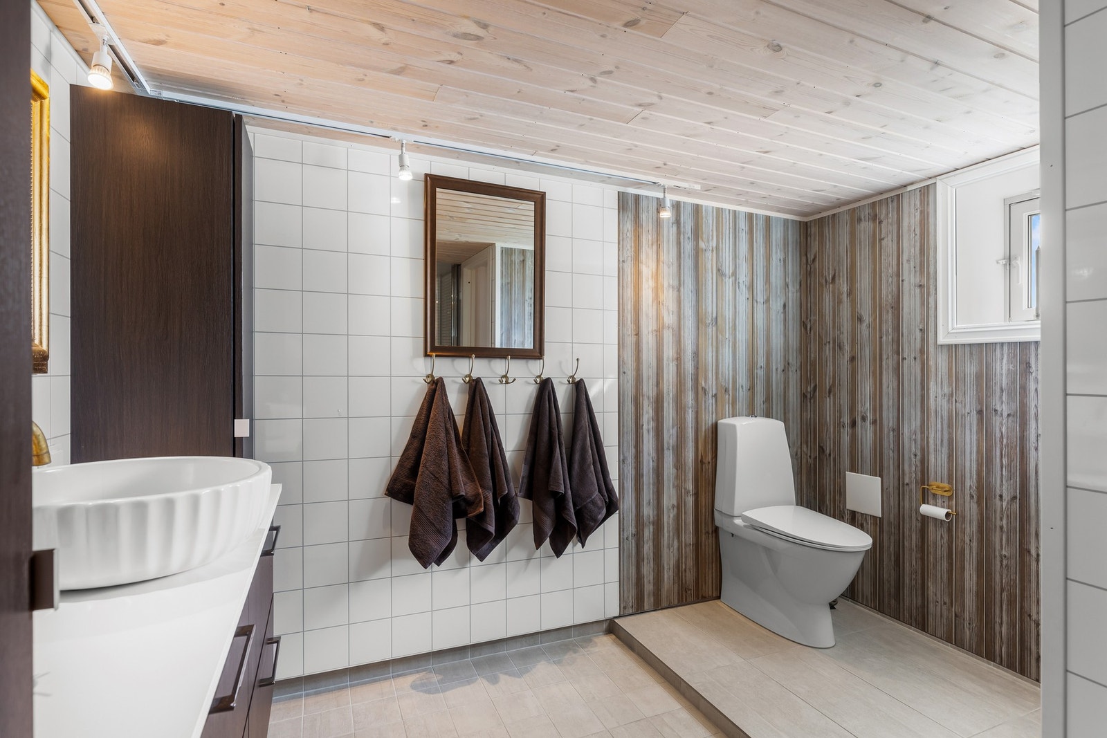 Badet inneholder ei romslig innredning med servant, toalett og dusjnisje. Det er varmekabler i gulv. Galleribilde