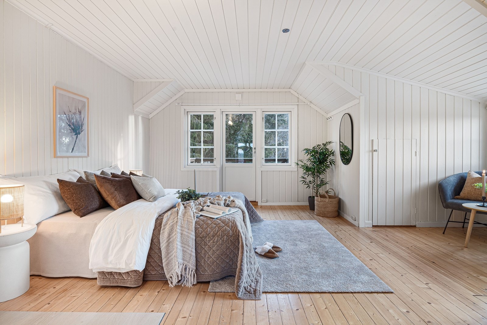 Stort og lyst hovedsoverom med lune tregulv og lysmalt panel på veggene. Galleribilde