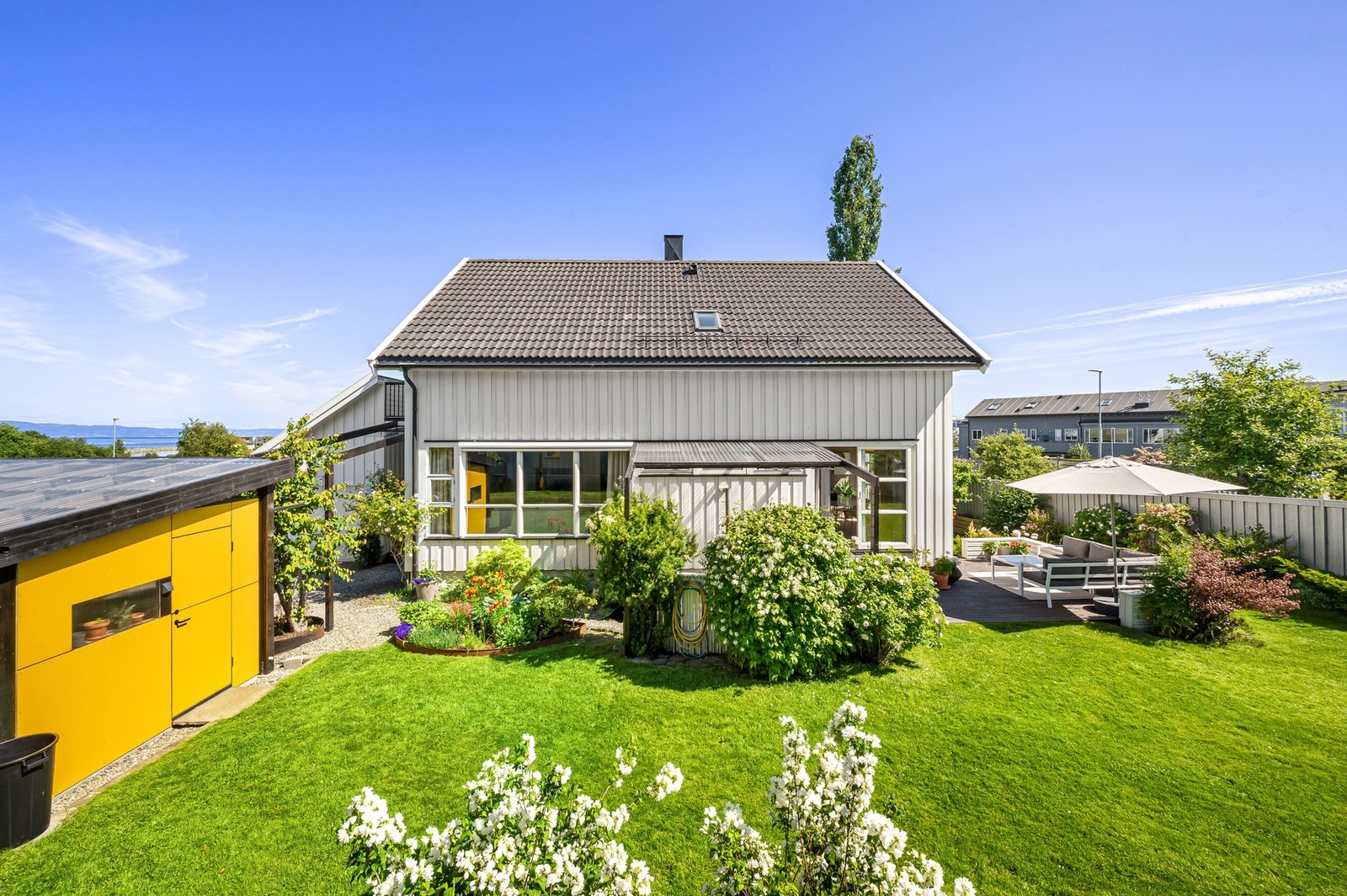 Velstelt hage, solrik terrasse og frodig beplantning - en idyllisk uteplass perfekt for avslapping og sosiale sammenkomster. Galleribilde